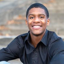 Cameron in a black button-up shirt on concrete steps.