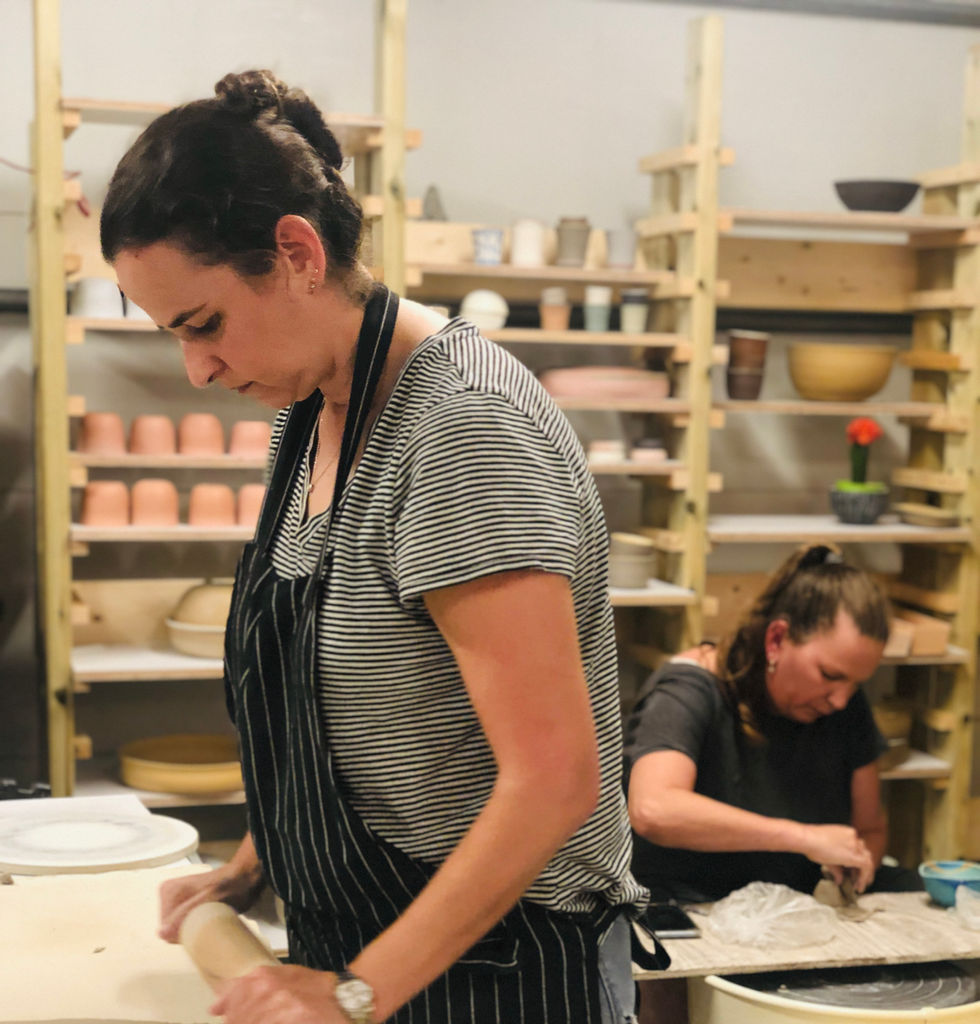 תלמידה מרדדת חימר על שולחן העבודה