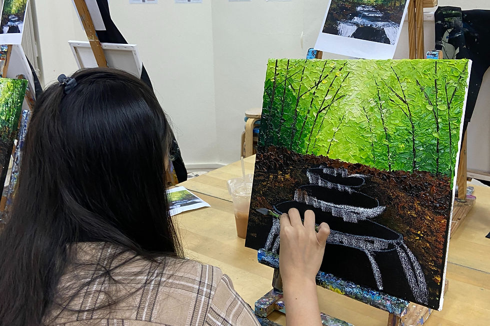 A participant of our acrylic palette knife painting workshop. They are painting a forest with a stream.