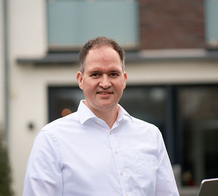 Mann in weißem Hemd vor Haus