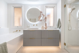 Luxurious modern bathroom renovation in Perth by Elite Makeovers. Featuring a stylish floating vanity with gold fittings, a round LED mirror, and a sleek walk-in shower. Expertly designed for elegance and functionality.