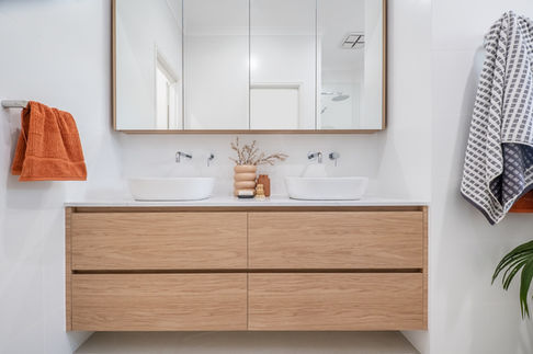 A modern Bathroom renovation with a twin round basin, chrome wall mounted tapware, and a pop of colour orange hand towel that ties up the whole entire look.