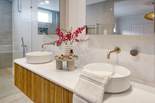Stylish bathroom renovation in Perth featuring a floating timber vanity with twin round basins, brushed brass tapware, and elegant décor. The warm wood tones and neutral palette create a natural, inviting aesthetic. Designed and built by Elite Makeovers, Perth’s experts in luxury bathroom renovations.