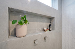 Elegant bathroom shower niche with built-in shelving, featuring soft grey tiles, minimalist tapware, and stylish decor. Designed by Elite Makeovers in Perth, this modern bathroom combines functionality with a sophisticated touch. Upgrade your space with premium renovations in Western Australia.