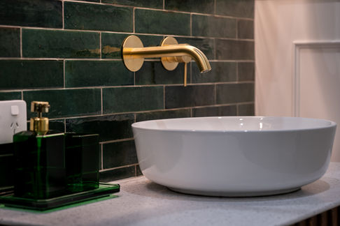 Close-up of an Art Deco-inspired bathroom vanity by Elite Makeovers, highlighting a white vessel basin, gold wall-mounted tapware, and rich green subway tiles for a timeless and elegant look. The wainscoting, expertly done by our team, adds a touch of classic charm and sophistication.