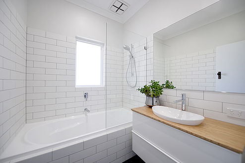 Bright and modern bathroom transformation with a white subway tile design, bathtub, and stylish floating vanity with a timber benchtop. A fresh and functional renovation by Elite Makeovers in Perth.