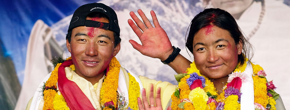 Mariage au sommet de l'Everest : Pem Dorjee et Moni Mulepati, couple népalais couvert de guirlandes de fleurs orange, saluant de la main