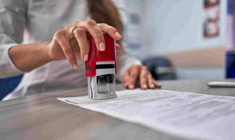 A notary holds their notary stamp over the portion of the document that requires they place their seal to notarize the document.