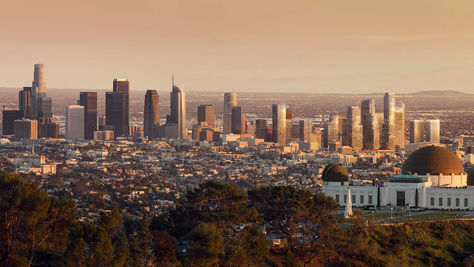 A picture of the sprawling Los Angeles skyline during sunset. In the foreground is the Griffith Park Observatory. In the background is the skyscrapers in Downtown Los Angeles. Scattered in between is all the homes, apartment buildings, shops, stores, and businesses that make up the city.