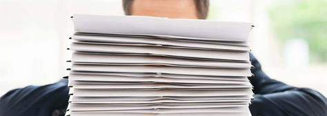 A notary public sits in front of a comically large stack of documents to notarize.