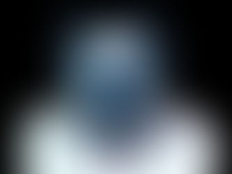 Ritrattto ravvicinato di un volto femminile che indossa una maschera a gatto creata dall'artista. La maschera è composta da strass blu oltremare lucidi e strass neri opachi. Dalla maschera partono strisce di brillantini blu cobalto che scendono sulla pelle verso il petto. Lo sfondo è nero. L'immagine esprime un forte impatto visivo