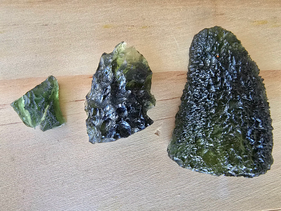 Small, medium and larger Moldavite pieces shown together for size comparison.