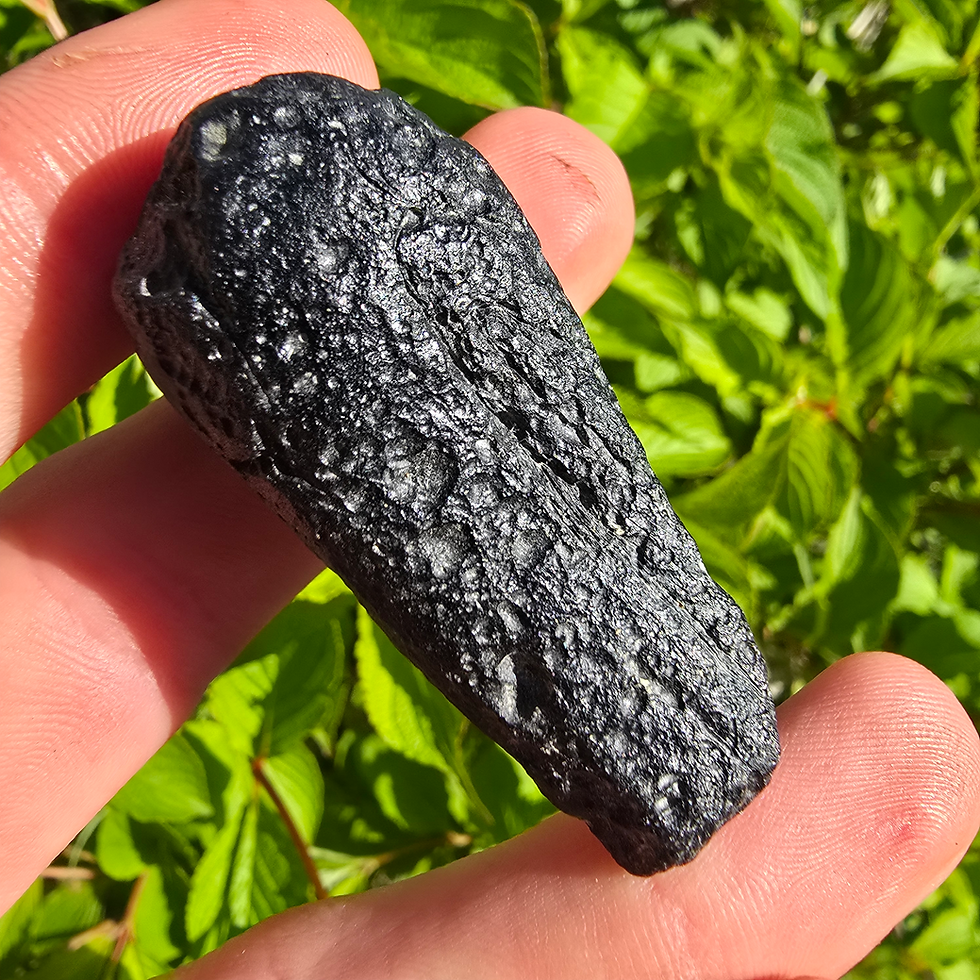 Thumbnail: Hand holding a dark, textured Vietnam Indochinite Tektite