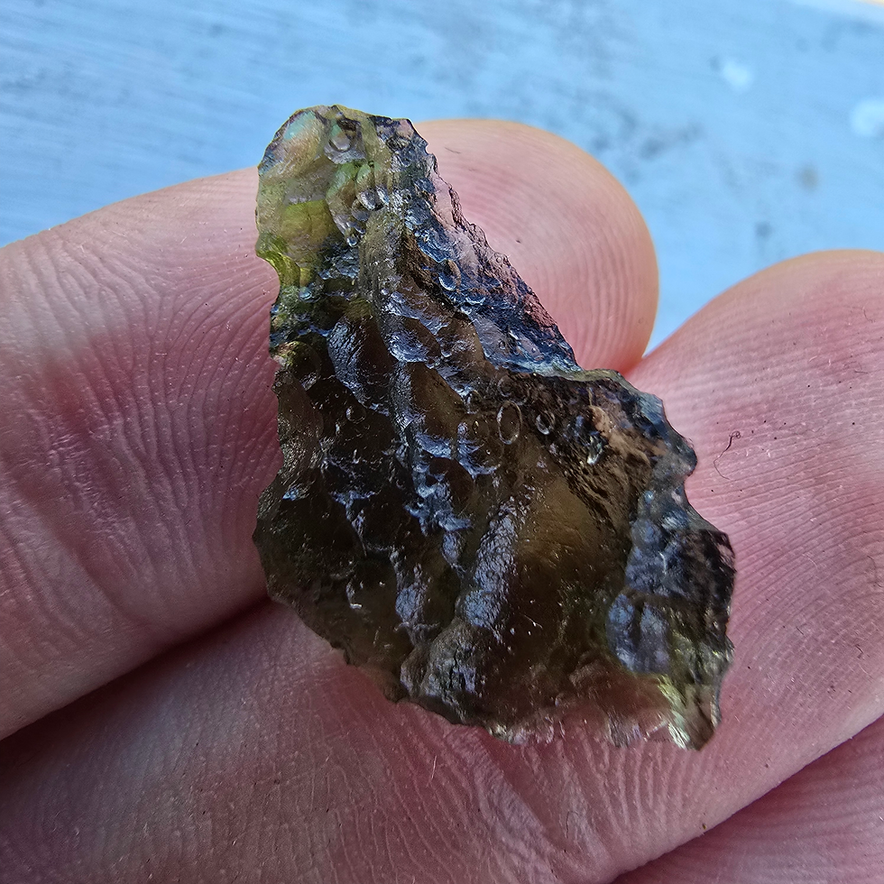 Thumbnail: Rough moldavite stone, 0.56g, held in hand