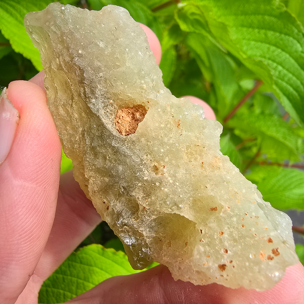 Thumbnail: Hand holding rough green moldavite