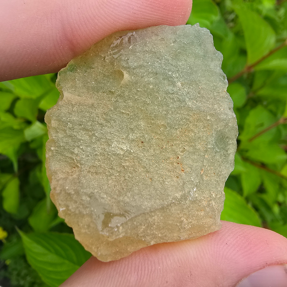 Thumbnail: Greenish-yellow Moldavite stone held between fingers