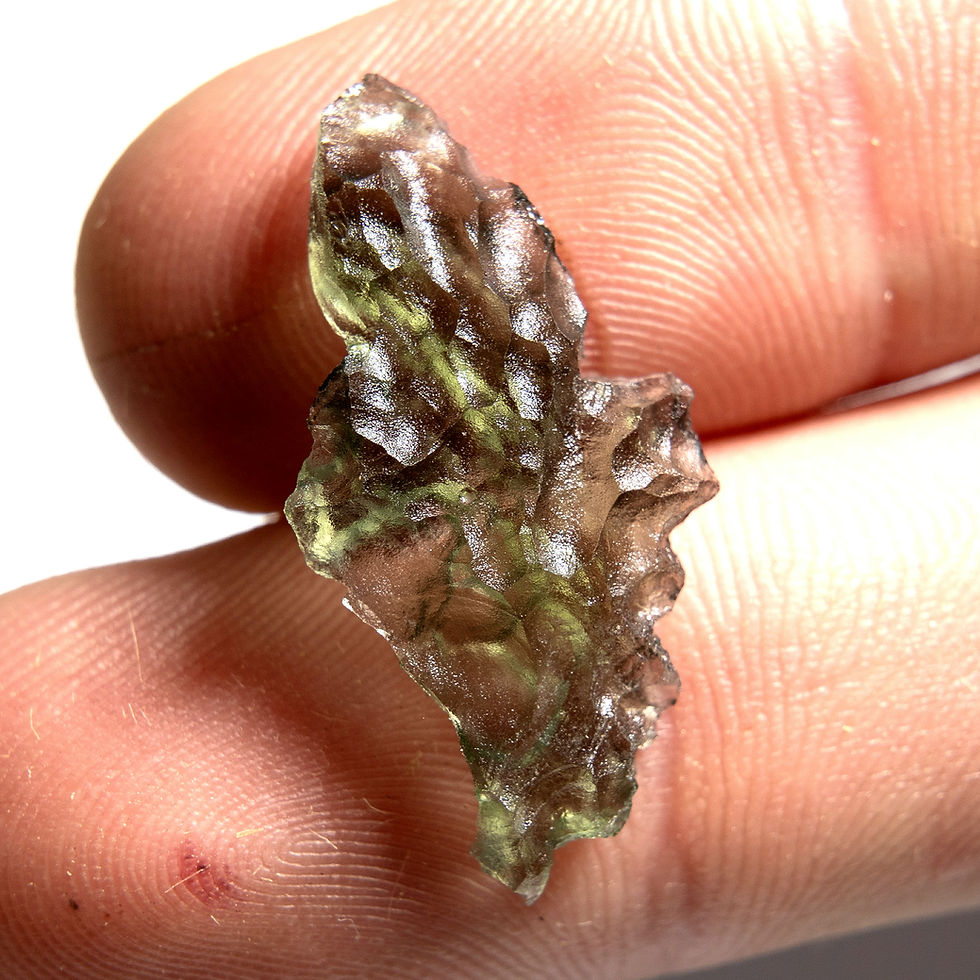 Thumbnail: Libyan Desert Glass shard held between fingers