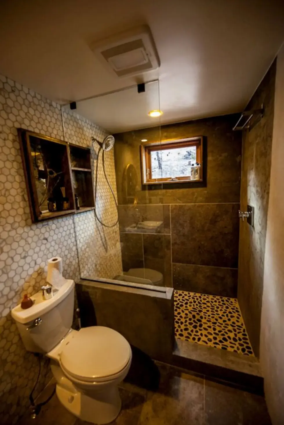 Luxury spa-style bathroom with walk-in shower, dark tile, and hexagonal wall tile in Boulder fine dining restaurant