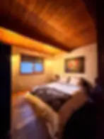 Cozy rustic bedroom with wooden ceiling, warm lighting, and mountain views at The Rusty Skillet