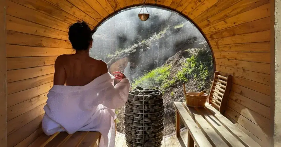 Person relaxing in wooden barrel sauna with mountain view window at Boulder County Fair wellness exhibit