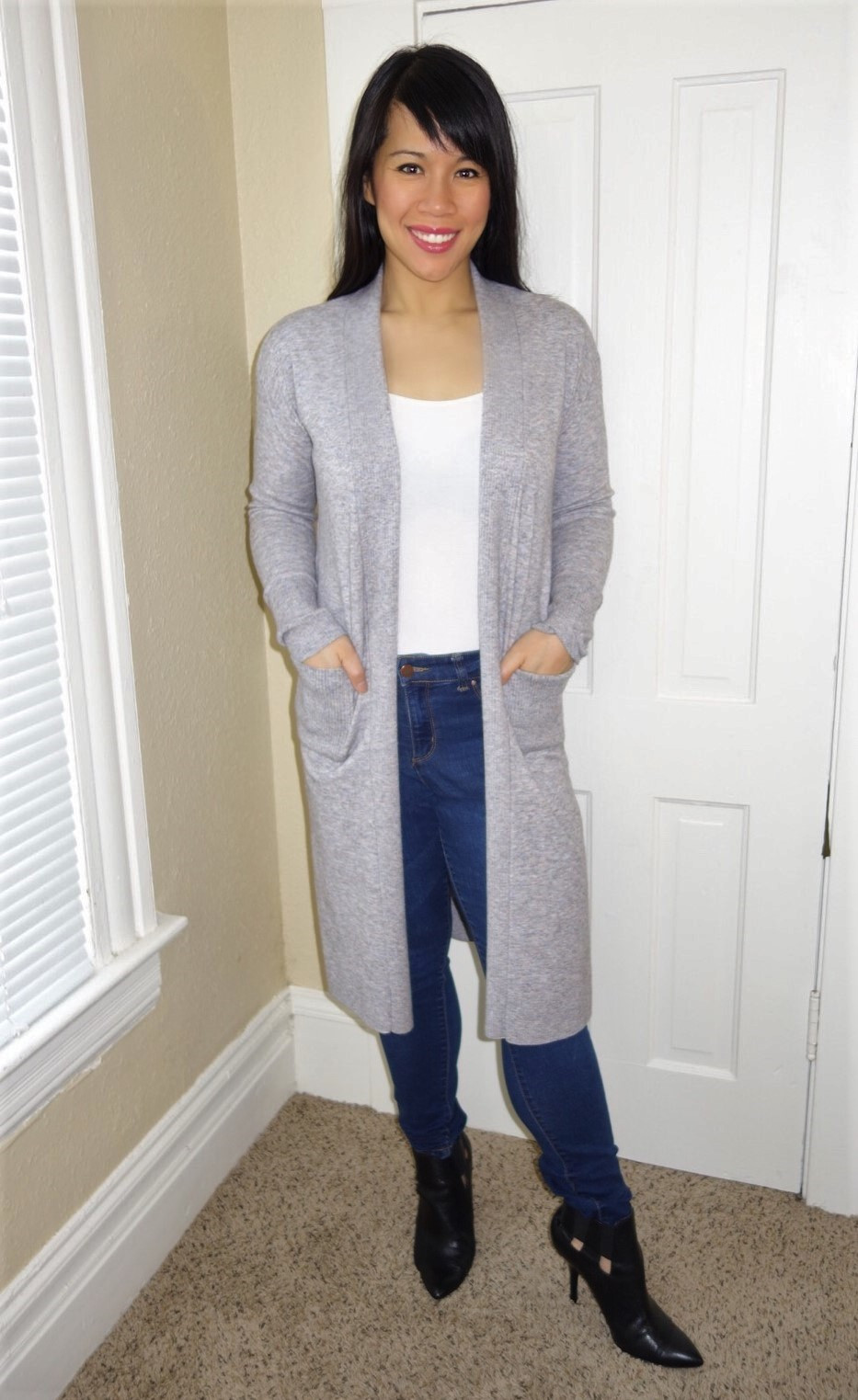 Kat wearing a grey duster, white tank, and blue jeans to illustrate minimalist style