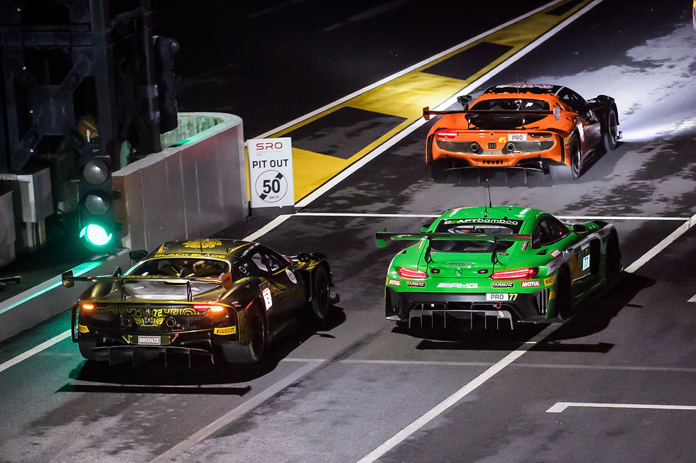 Three GT race cars exit pit lane under green light, with SRO PIT OUT 50 sign.