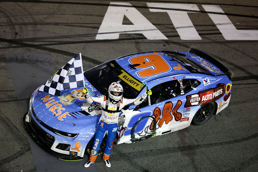 Race car driver celebrates on a blue car with a checkered flag. Car has number 9 and sponsor logos. "ATL" on track in the background.