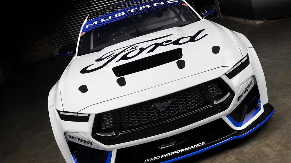 White Ford Mustang race car with bold "Ford" logo on hood, "Mustang" on windshield. Blue accents. Parked in a dim garage.