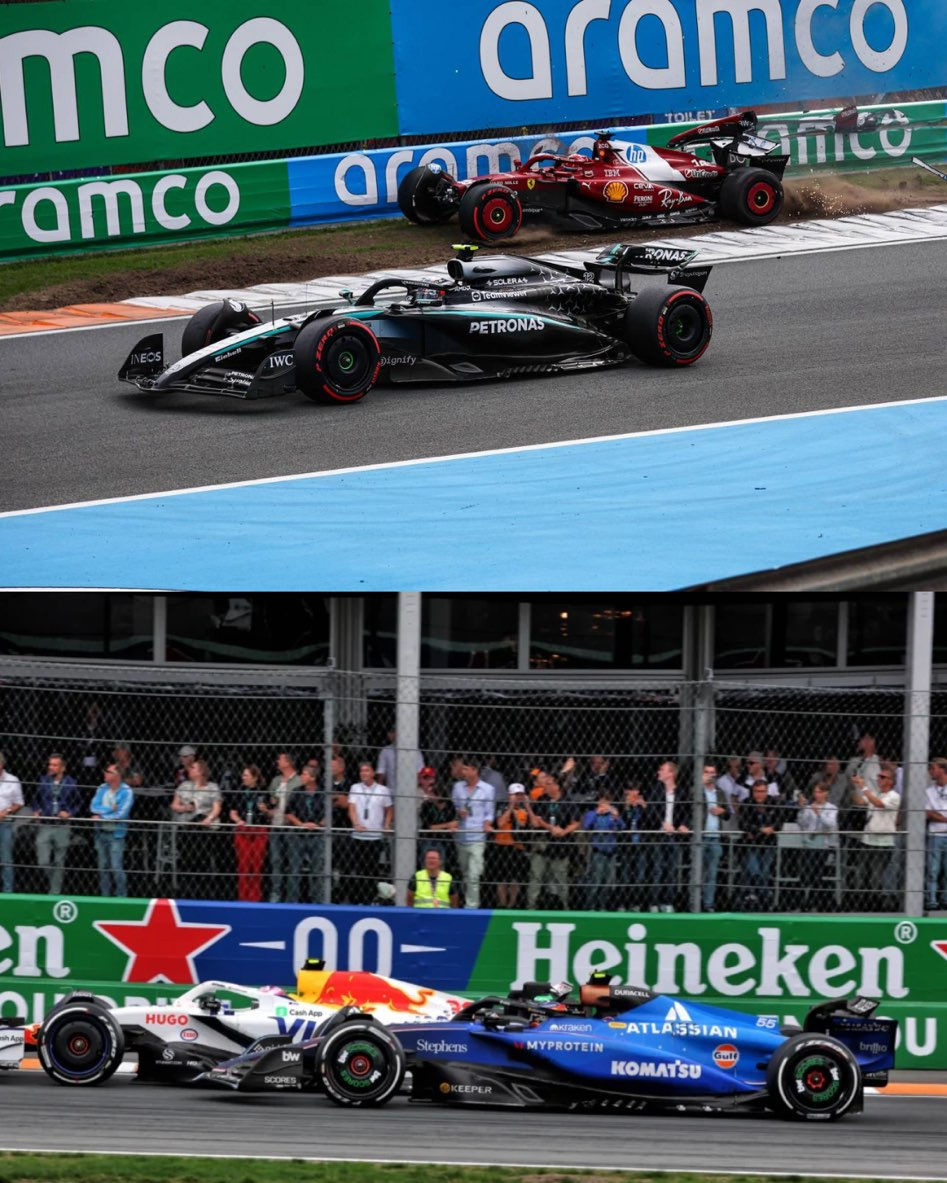 Four Formula 1 cars race on track with Aramco and Heineken ads in background. Spectators watch behind the fence. Cars in black, red, blue.
