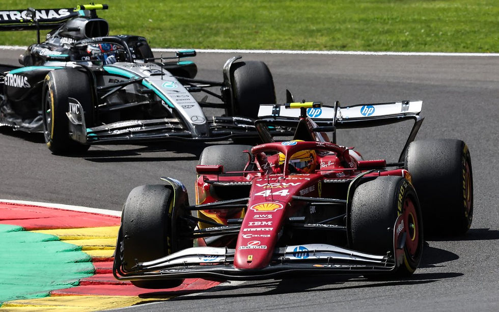 Two Formula 1 cars race on a track. A red car with number 44 leads a silver car. Colorful curbs and grass line the circuit.