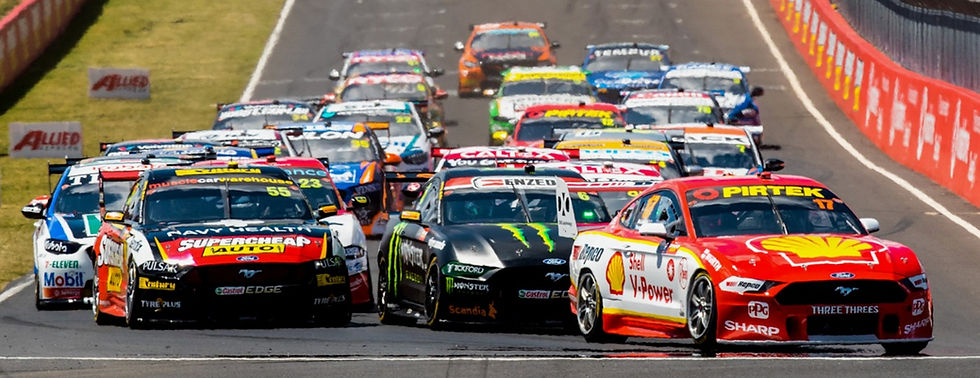 Race cars compete on a track, led by a red Shell car. Vibrant colors and sponsor logos create an intense, dynamic scene.