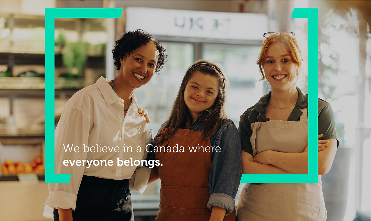 Three coworkers standing in a grocery store. Two of them are wearing aprons and one has Down syndrome. A teal colour square bracket graphic surrounds them. Text reads "We believe in a Canada where everyone belongs."