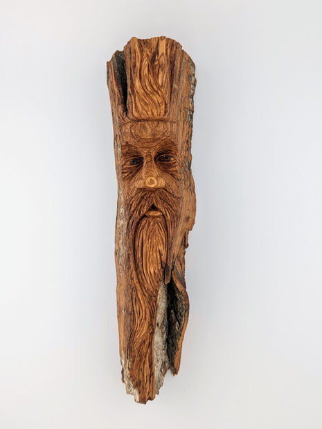 a carving of a male face with a beard in a piece of wood