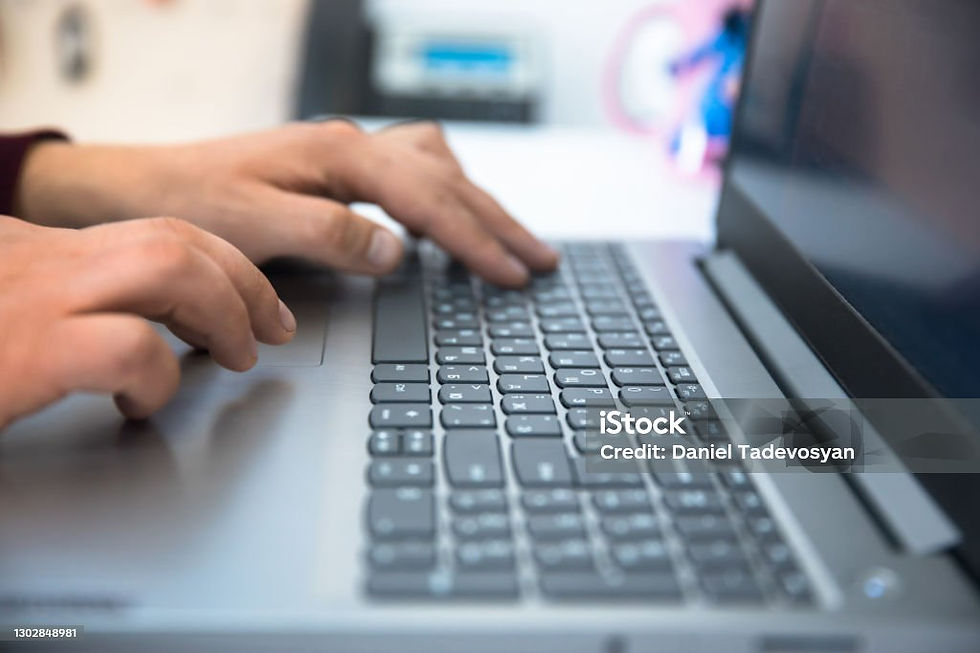 A close up image of a laptop with a person's hands typing on the keyboard.