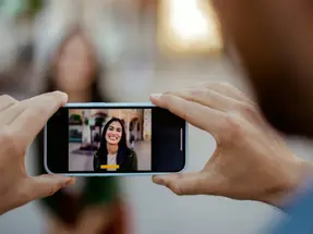 A man taking a photograph of a woman using a smartphone camera