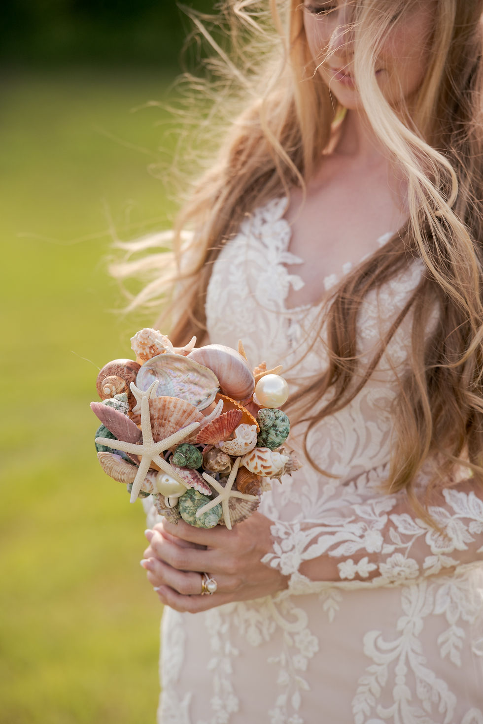 The bride looks down at her custom made sea shell Wedding bouquet.