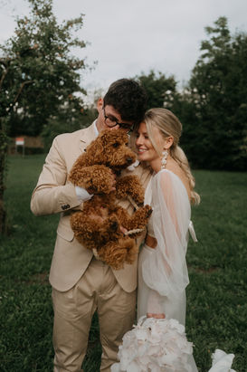 Ungestelltes Portrait von Braut, Bräutigam und ihrem Hund bei der Hochzeit, festgehalten von einem Hochzeitsfotografen für authentische Momente.