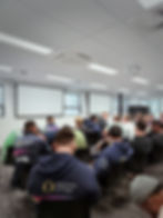 rugby players seated in a meeting room, participating in an oral health workshop. 