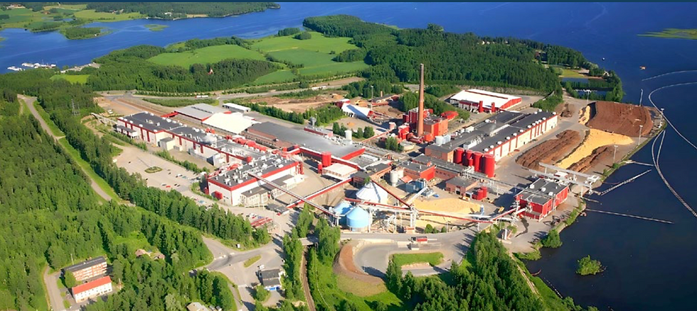 Aerial view of an industrial complex Corsair Group International with red and white buildings, surrounded by green forests, near a blue lake. Bright and clear atmosphere.