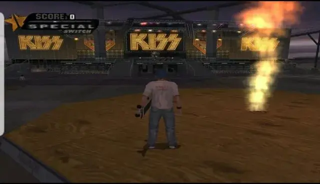 An image clip from the video game " Tony Hawk's Underground". in the clip a male skate border stnd on top a of a skateboarding platform , while holding a skate board , watching a music stage with a kiss themed concert backdrop.
