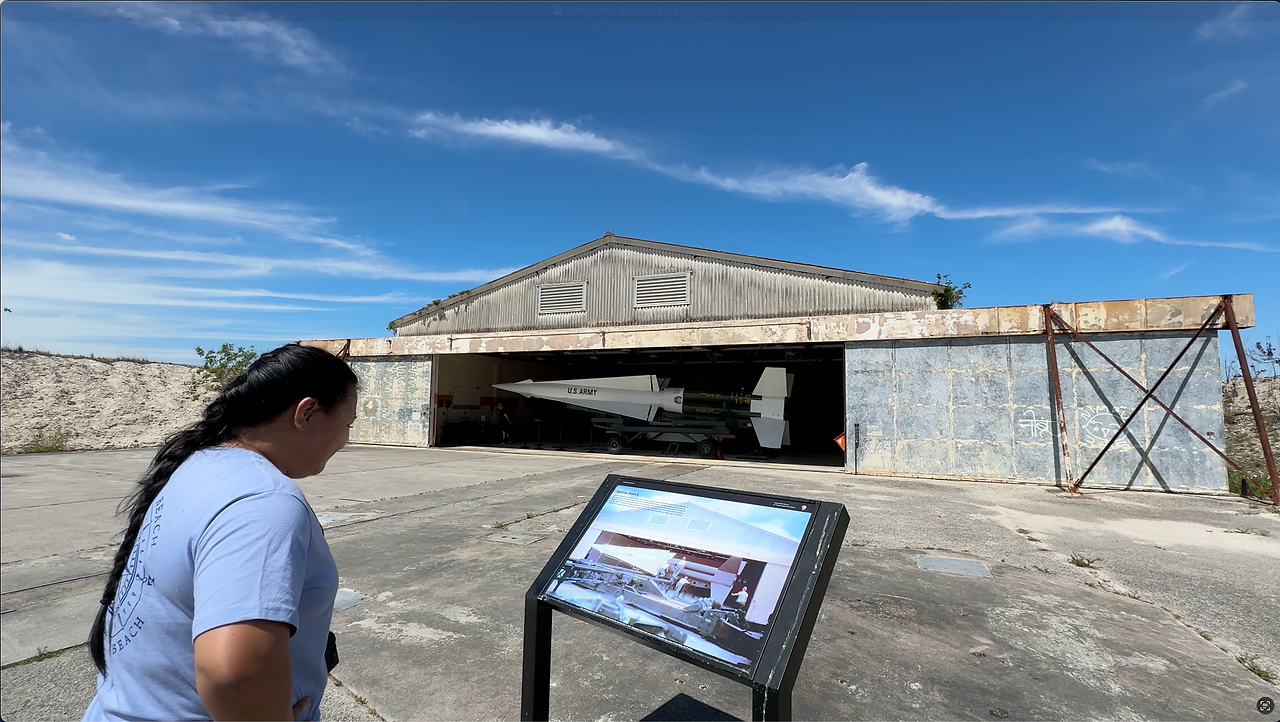 Chrissa reading an informational sign with the Nike Missile in a barn in the background