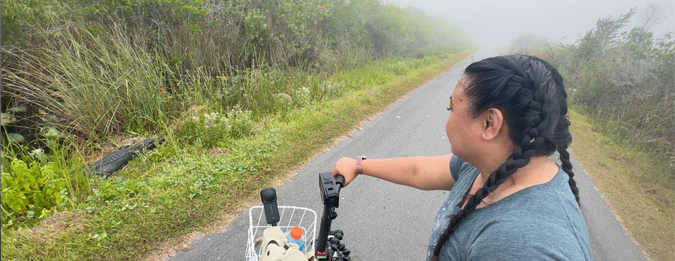 Chrissa on a bicycle looking down at an alligator