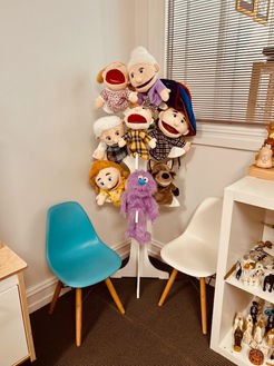Counselling room corner with puppets, chairs, and play therapy tools for child-focused sessions.