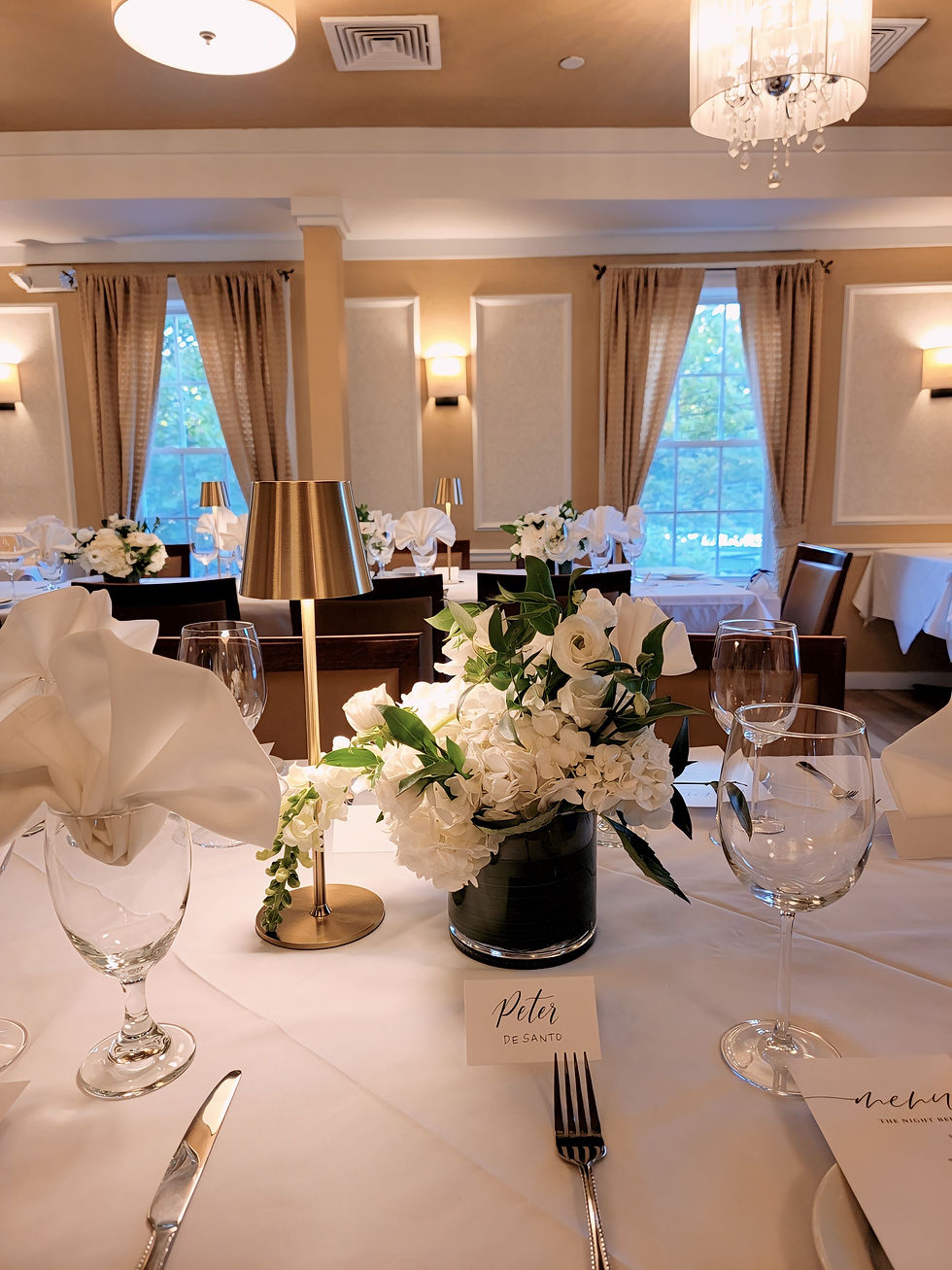 Beautifully decorated tablescape with floral arrangements, mini table lamps, and name cards set up for a thoughtful event.