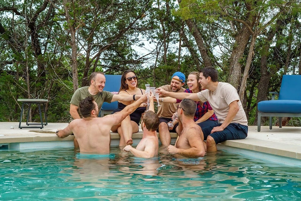 People in a pool doing a 'cheers' with champagne glasses.