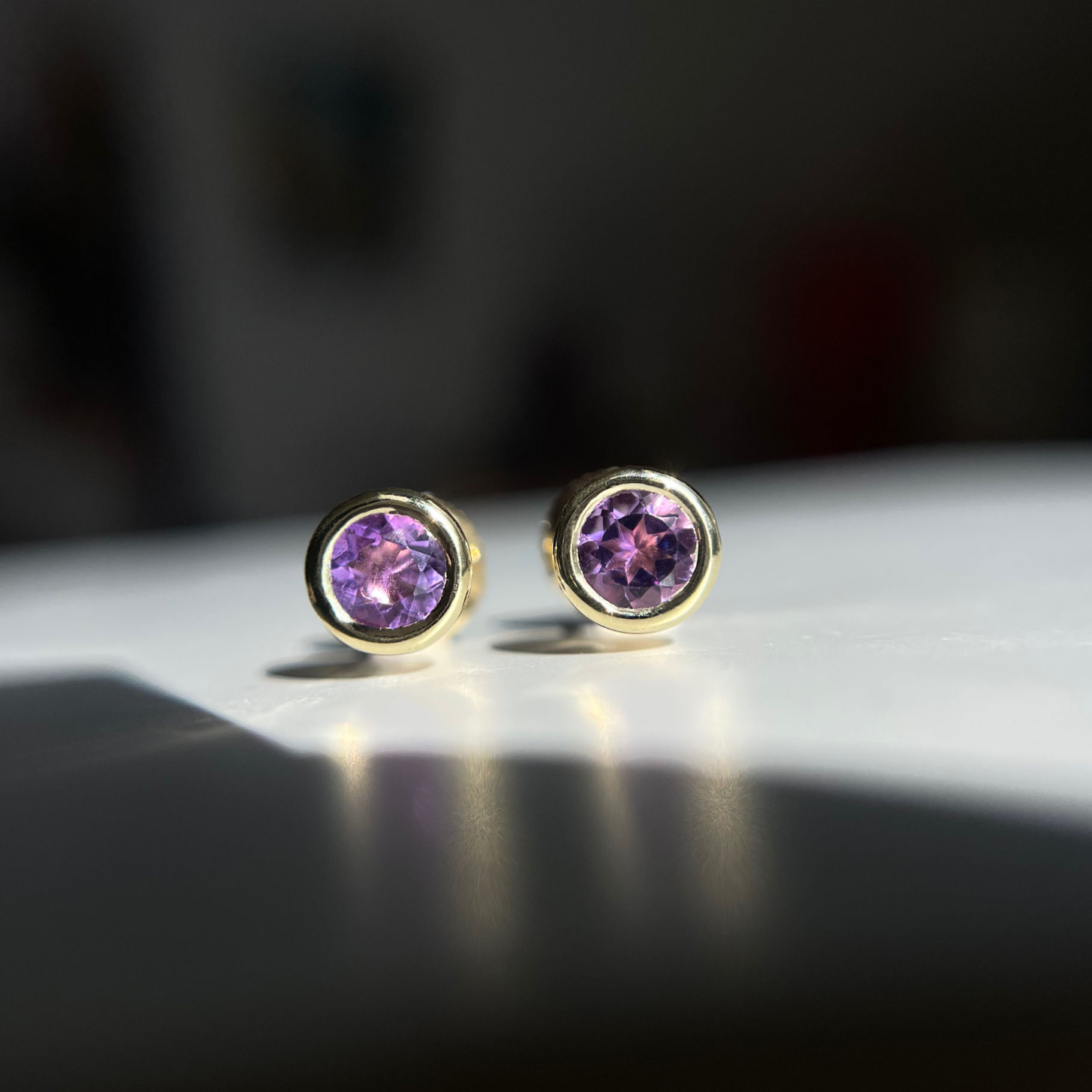 Minimalist yellow gold earrings with violet gemstones — refined and timeless