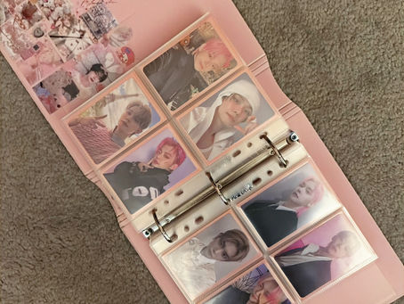 Pink photo album on carpet, filled with photocards of Yeonjun; some have pink hair. Decorated cover with stickers.