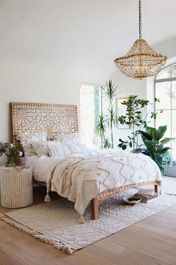 Rattan chandelier plants patterned rug hand carved wood headboard