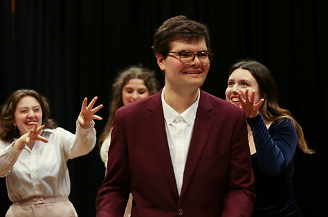 A male cast member surrounded by 3 female scary-looking cast members on stage as part of the cast for the theatrical production "Dinner With Gatsby"