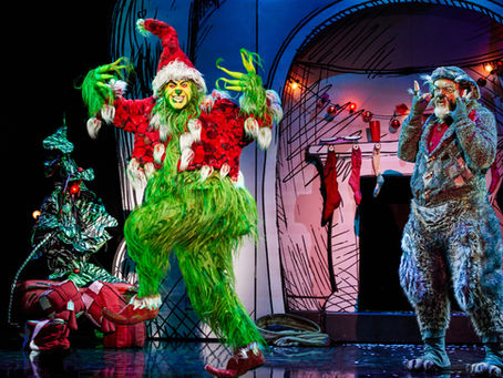 The Grinch, dressed as Santa Claus, is in a sneaky pose, while Old Max watches on in front of a Dr. Seuss-inspired set.